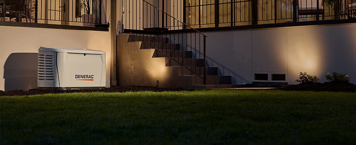 Generac air-cooled home standby generator beside a house at night